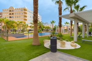 een park met palmbomen en een zwembad bij 1 Bed Apartment Abedules Residence in El Campello