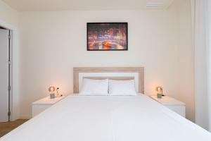 een slaapkamer met een groot wit bed en 2 nachtkastjes bij 1 Bed Apartment Abedules Residence in El Campello +23 foto's