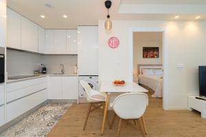 een keuken met witte kasten en een tafel en stoelen bij 1 Bed Apartment Abedules Residence in El Campello