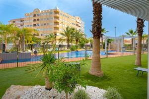 een resort met een zwembad en palmbomen en een gebouw bij 1 Bed Apartment Abedules Residence in El Campello