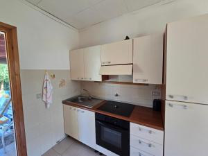 kuchnia z białymi szafkami i czarnym piecem w obiekcie Appartamento verde w mieście Porto Azzurro