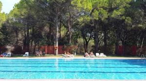 a group of people sitting in lawn chairs near a swimming pool at Mobilehome in Aquileia 50114 in Aquiléia