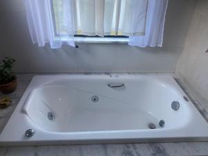 a white bath tub in a bathroom with a window at Chalé do Canto - Pé da Serra in Lima Duarte
