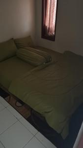 a green bed in a room with a window at Tomo Homestay in Ngasinan +3 photos