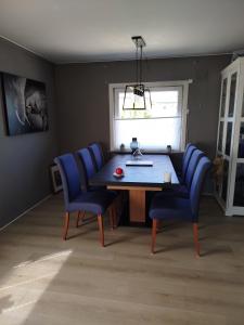a dining room table with blue chairs and a window at Margaret's Home in Nøtterøy