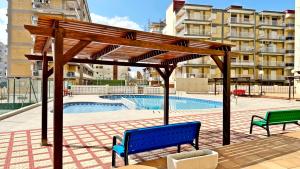 drewniana pergola z dwoma ławkami obok basenu w obiekcie NEPTUNO GANDIA Primera Línea - Alquiler Familias w mieście Playa de Gandia