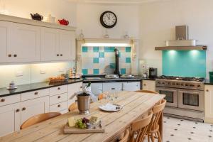 a kitchen with a wooden table and a clock on the wall at Tamar Castle in St Mellion