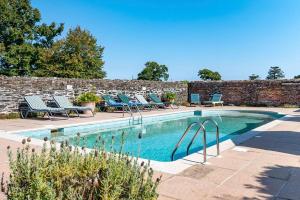 a swimming pool with lounge chairs next to a brick wall at Tamar Castle in St Mellion