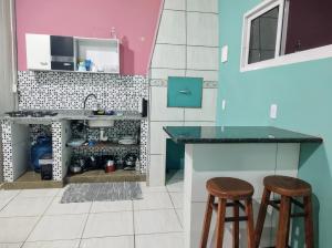 Una cocina con dos taburetes de bar y un fregadero. en Apto com churrasqueira 500m do mar com vista da salaSacada para horizonte, en São Francisco do Sul