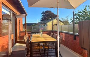 un tavolo in legno e sedie su un balcone con ombrellone di 3 Bedroom Lovely Home In Strandby a Strandby