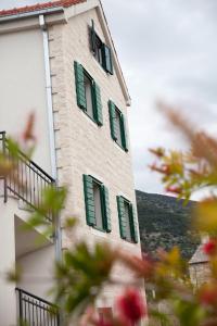 a building with green shutters on the side of it at Apartments Baričević in Bol