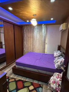 une chambre avec un lit violet et un plafond bleu dans l'établissement Madinty b7, à Madinaty