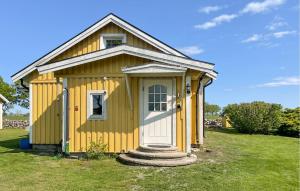 a yellow shed with a white door in a yard at Holiday Home N, Honungstorp Löttorp in Löttorp