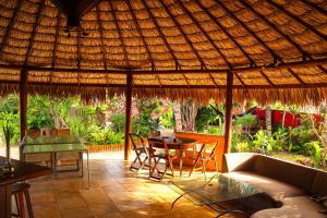 a living room with a couch and a table under a straw roof at Pousada Casa do Jardim in Canoa Quebrada