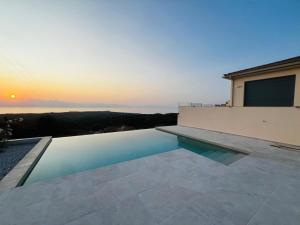 a swimming pool on top of a house with the sunset at Villa Sunrise in Chrisokellaria