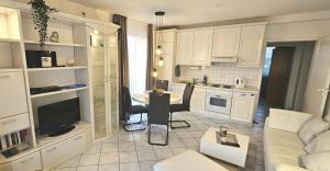 a kitchen with white cabinets and a living room at Apartment "Seeschwalbe" mit sonnigem Südbalkon Sauna und Parkplatz - 200m zum Deich in Holssel