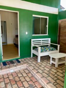 um quarto com uma parede verde com uma cama e um banco em Vila Goa em Cruz