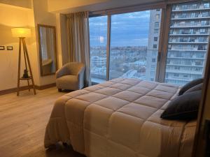 a bedroom with a large bed and a large window at Departamento espectacular con balcón panorámico en piso alto in Villa Marini +12 photos