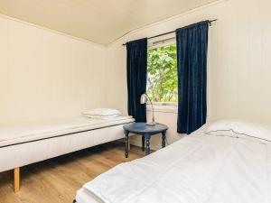a bedroom with two beds and a table with a lamp at 6 person holiday home in Løkken in Løkken