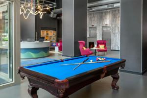 a pool table in a room with pink chairs at Aloft by Marriott New York Brooklyn in Brooklyn