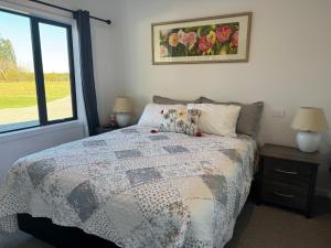 um quarto com uma cama com uma colcha e uma janela em Bellbird Hideaway em Pleasant Valley
