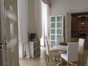 a dining room with a table and white chairs at Palazzo Doxi Fontana Dimora Storica in Gallipoli