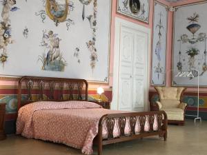 a bedroom with a bed and a chair and wallpaper at Palazzo Doxi Fontana Dimora Storica in Gallipoli
