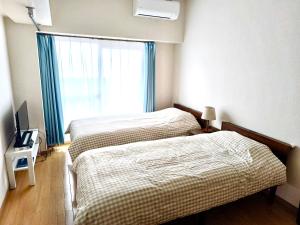 two beds in a hotel room with a window at 鹿鸣新荣507 in Nagoya