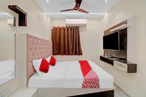 a bedroom with a bed with red pillows and a tv at Hotel O S R Guest House in Sakardarā