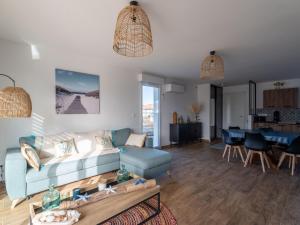 a living room with a blue couch and a table at Maison moderne à 6 km de Mimizan pour 6 personnes, ménage inclus - FR-1-50-156 in Saint-Paul-en-Born