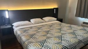 a large bed with two pillows on top of it at Motel 6 Modesto, CA in Modesto