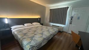 a bedroom with a bed with a comforter and a window at Motel 6 Modesto, CA in Modesto