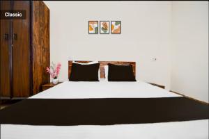 a bedroom with a large white bed with black pillows at The Vasudha Estate in Lucknow
