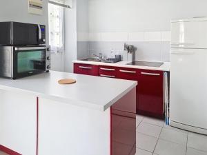 una cucina con armadi rossi e piano di lavoro bianco di Studio proche mer à Saint-Aubin-sur-Mer - FR-1-746-32 a Saint-Aubin-sur-Mer Altre 4 foto