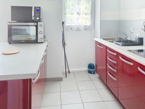 una cucina con armadi rossi e forno a microonde di Studio proche mer à Saint-Aubin-sur-Mer - FR-1-746-32 a Saint-Aubin-sur-Mer