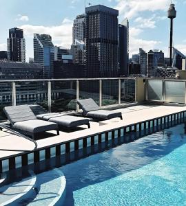 a rooftop pool with lounge chairs and a city skyline at Elegant Hyde Park View Retreat With Gym & Rooftop Pool in Sydney +36 photos