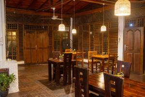 a dining room with wooden tables and chairs and lights at Oasis Bay - Arugam Bay in Arugam Bay