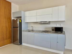 a kitchen with white cabinets and a stainless steel refrigerator at Loft a few blocks from the beach in Mazatlán