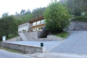 un bâtiment avec un arbre en face d'un mur de pierre dans l'établissement Pála dos Mouros, à Gerês