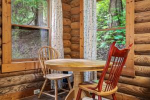 een tafel en twee stoelen in een hut met een raam bij Log Cabin, In-Room Jacuzzi, WiFi, Fireplace in Sevierville