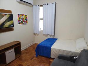 Un dormitorio con una cama, un televisor y un sofá. en Kitnet na Princesa Isabel no 10 andar, en Río de Janeiro