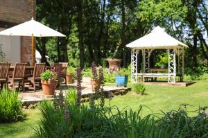 a gazebo in a garden with chairs and an umbrella at The Brick House Annexe in Beaulieu