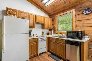 a kitchen with wooden cabinets and a white refrigerator at Hot Tub, Close to Everything, Honeymoon Cabin in Sevierville