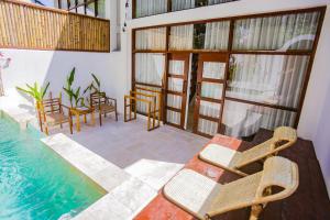 a room with a table and chairs next to a swimming pool at Vesuvio Loft Private Pool By Casa Kapuas in Gili Trawangan