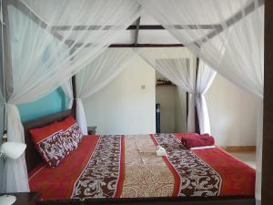 a bedroom with a canopy bed with red and white pillows at Bumbung Bungalows in Amed