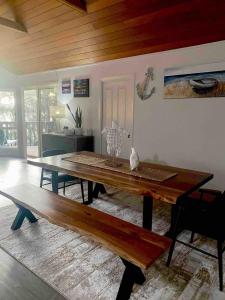 a dining room with a wooden table and a bench at The Lake House on Amaroo in Smiths Lake +21 photos