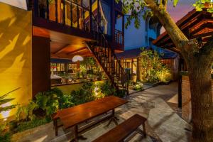 a wooden bench in front of a building with a staircase at DEMIN VILLA HỘI AN - POOL & BBQ Gaden in Hoi An