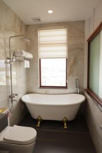 a bathroom with a tub and a toilet and a window at Cát Tường Hotel in Da Lat