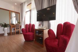 a living room with red chairs and a flat screen tv at Cát Tường Hotel in Da Lat