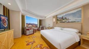 a bedroom with a large white bed and a television at Vienna Hotel Qinghai Yushu Tangfan Avenue in Chumda +85 photos